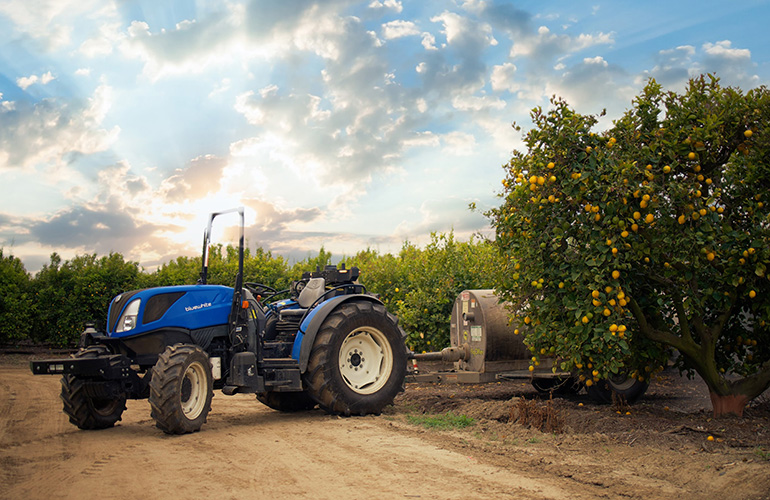 A CNH autonomous tractor emerges from an orchard.