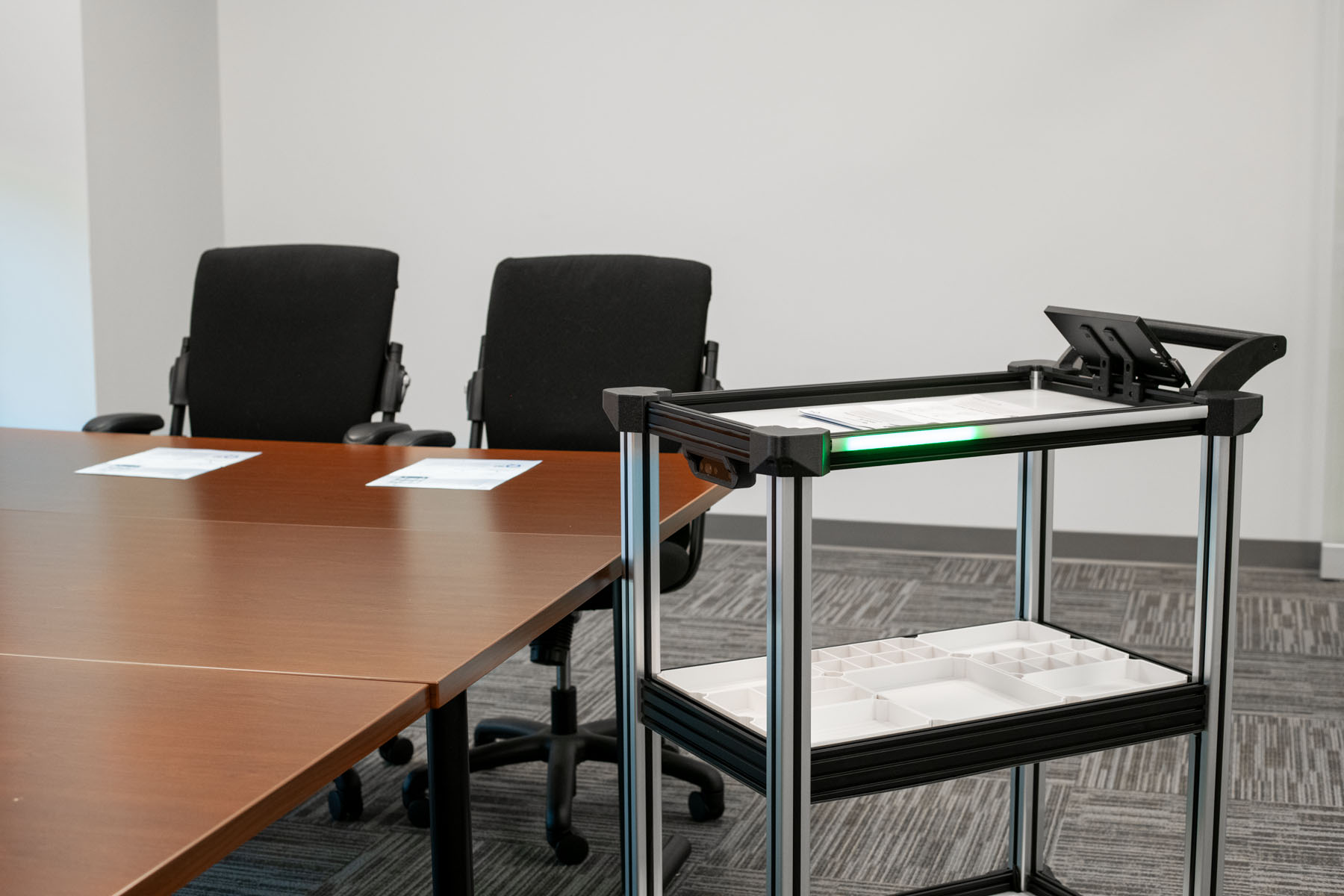 An image of a table with two black chairs with Quasi Robotics' C2 AMR in the foreground. 