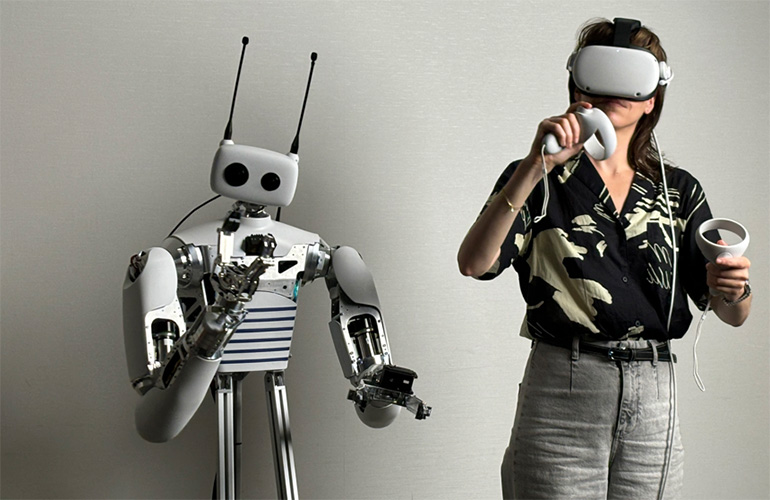 reachy robot next to a human with a visor and hand controller.